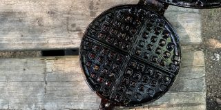 A small cast iron waffle pan open on a picnic table.