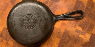 The back side of a small cast iron pan sitting atop a cutting board.